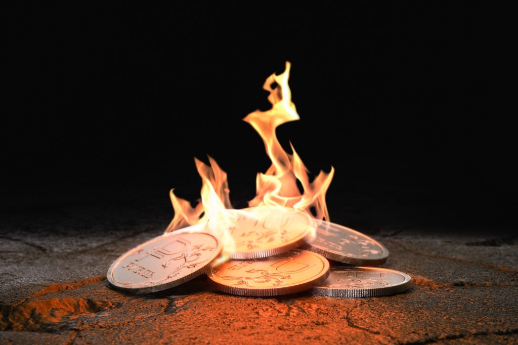 Russian Ruble coins burning on black background. Concept loss of value and inflation
