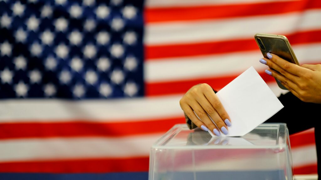 woman putting a ballot in a ballot box on election day.